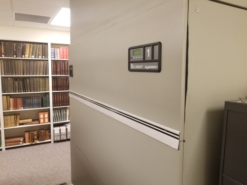 A large gray Leibert HVAC unit situated in the archival storage area